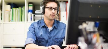 软件专业人员坐在计算机上戴耳机找新生涯 启动软件质量保证证书课程SAQ102